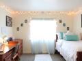 A dorm room with photos, string lights, and posters hanging on the walls