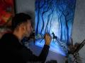 Someone painting a glow-in-the-dark image of a horse surrounded by trees
