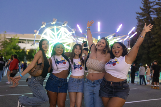 Group posing in front of lit-up carnival