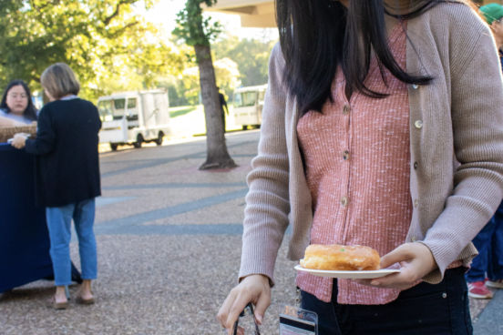 Someone reaches for a donut with tongs