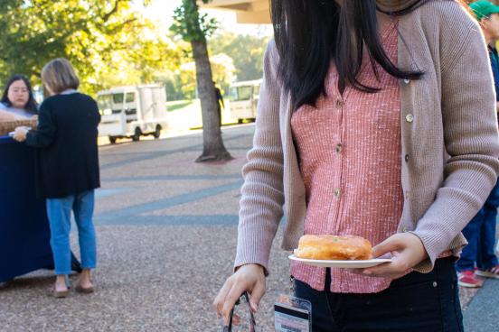 Someone reaches for a donut with tongs
