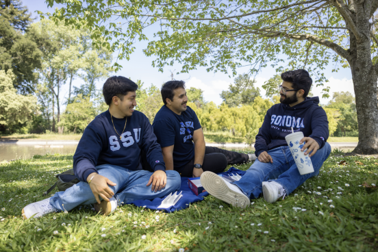 Three students laugh and talk by the lakes
