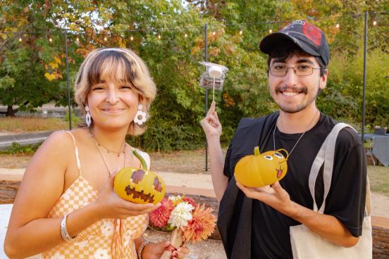Students hold up painted pumpkins