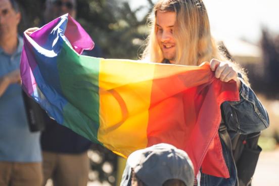Student holding a pride flag in crowd