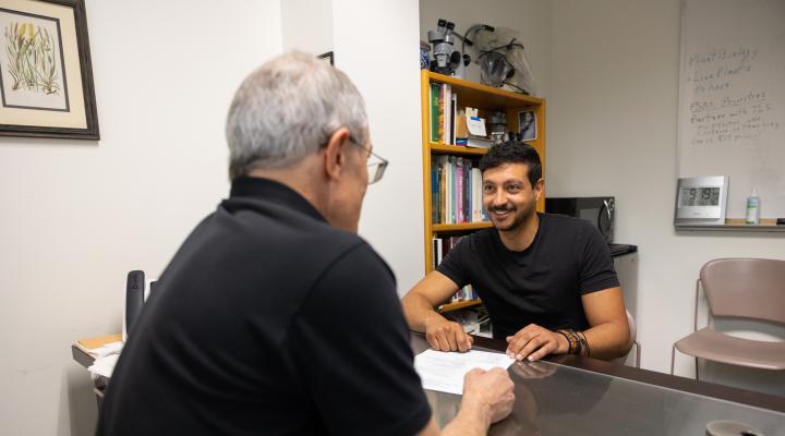 Student talking to a faculty member in their office with a piece of paper in front of them