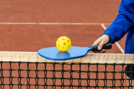 Someone balancing a ball on a pickleball racket