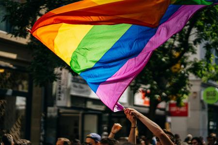 Someone waving a large pride flag in the air