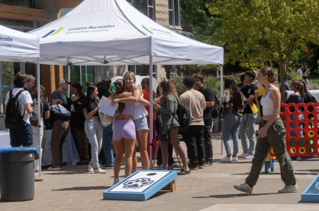 Students mingle around tented plaza