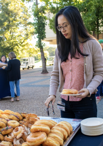 Someone reaches for a donut with tongs