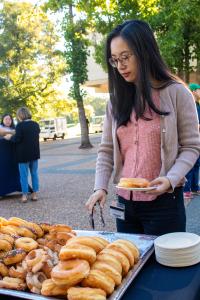 Someone reaches for a donut with tongs