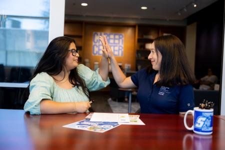 Two people high five in the career center