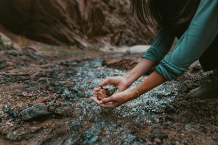 Someone gathering rocks by a stream