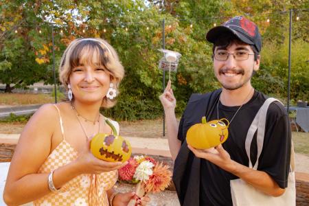 Students hold up painted pumpkins