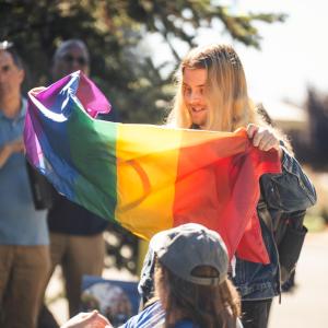 Student holding a pride flag in crowd