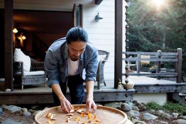 Someone arranging pieces of food over a large platter in an indoor/outdoor setting 