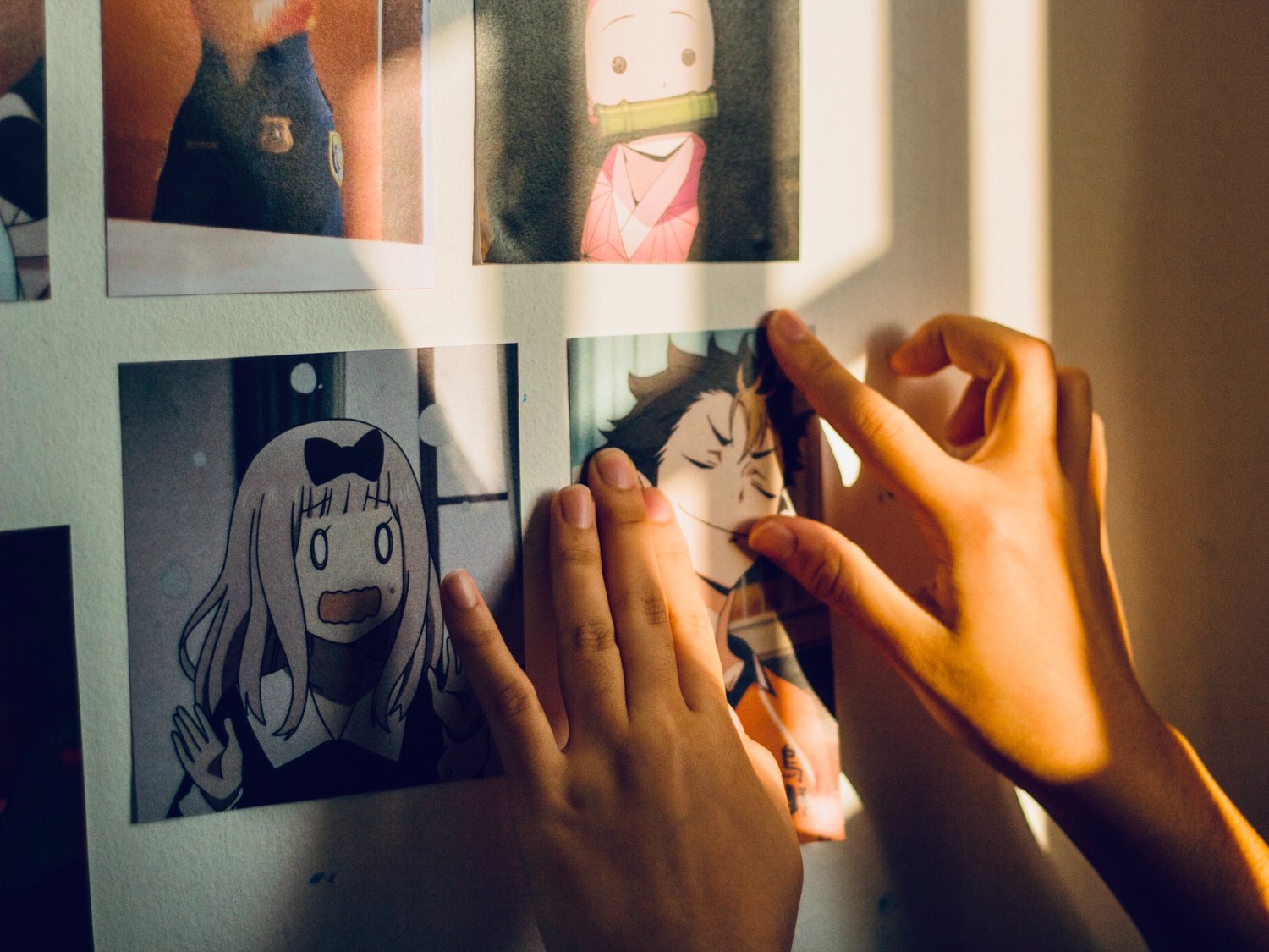 Someone's hands hanging anime artwork on a wall