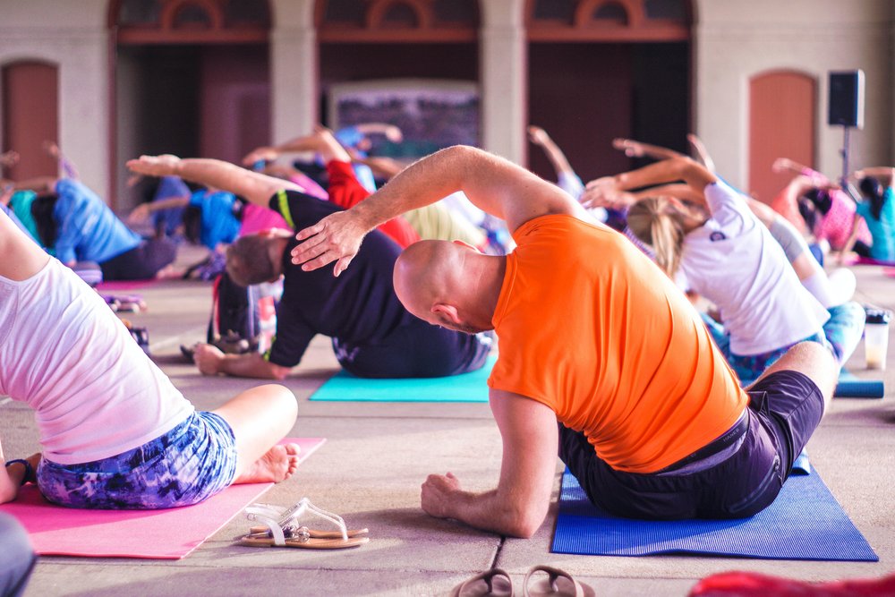 A group of people doing yoga stretches indoors 