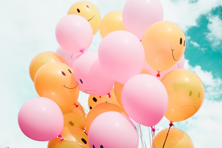 A bunch of pink and yellow balloons with smiley faces on them