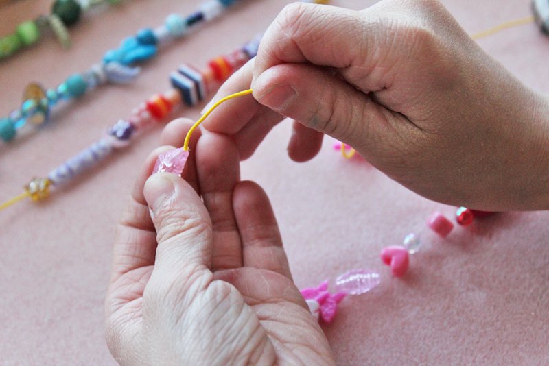 Someone stringing colorful beads onto string to make a bracelet