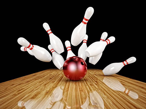 Bowling pins being knocked into the air by a red bowling ball