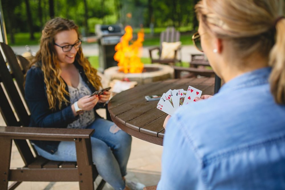 Two people playing card games on an outdoor table