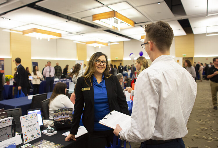 People smiling and talking in professional attire in an indoor setting 