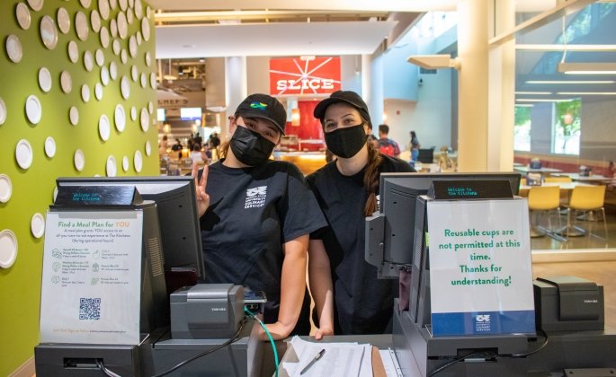 Cashiers posing in face masks behind their cash registers