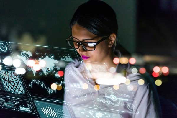 A person behind a computer screen with graphs on it