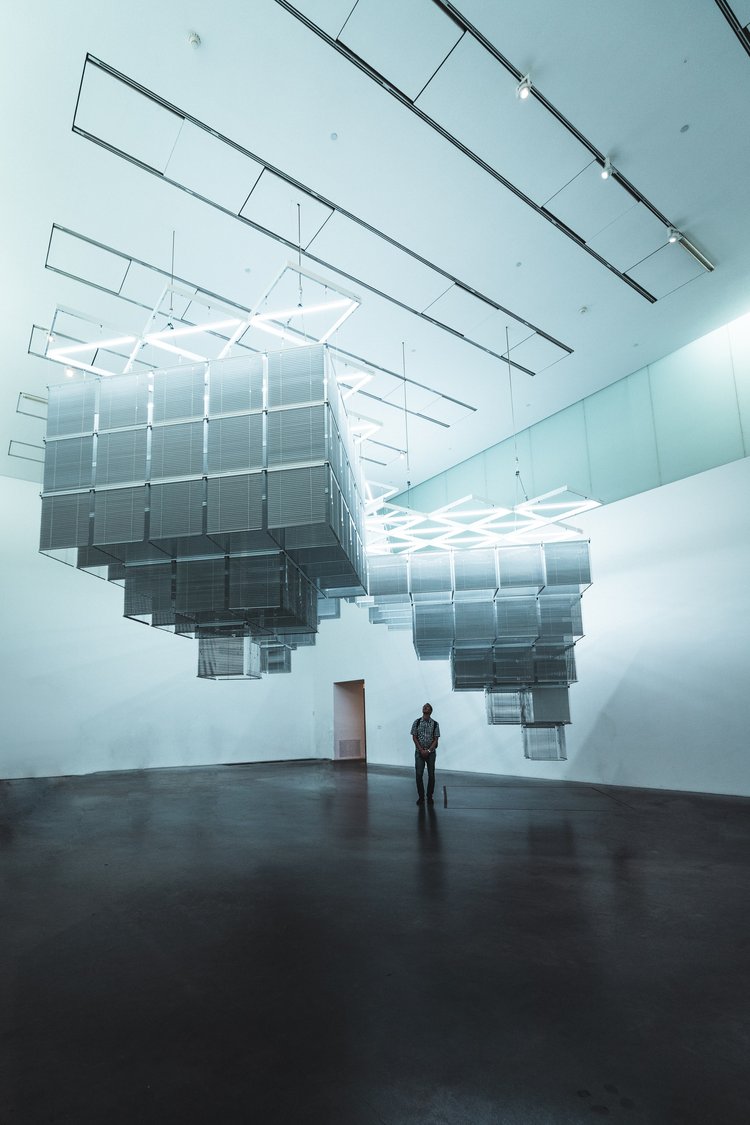 Someone looking at a hanging art installation in a museum