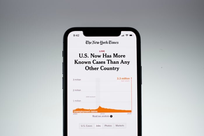 An iphone screen displaying a New York Times article titled "U.S> Now Has More Known Cases Than Any Other Country"