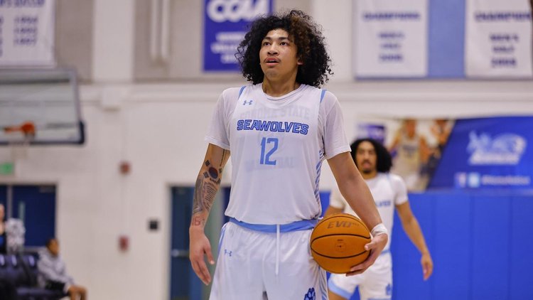 A member of the men's basketball team with a basketball in their hand