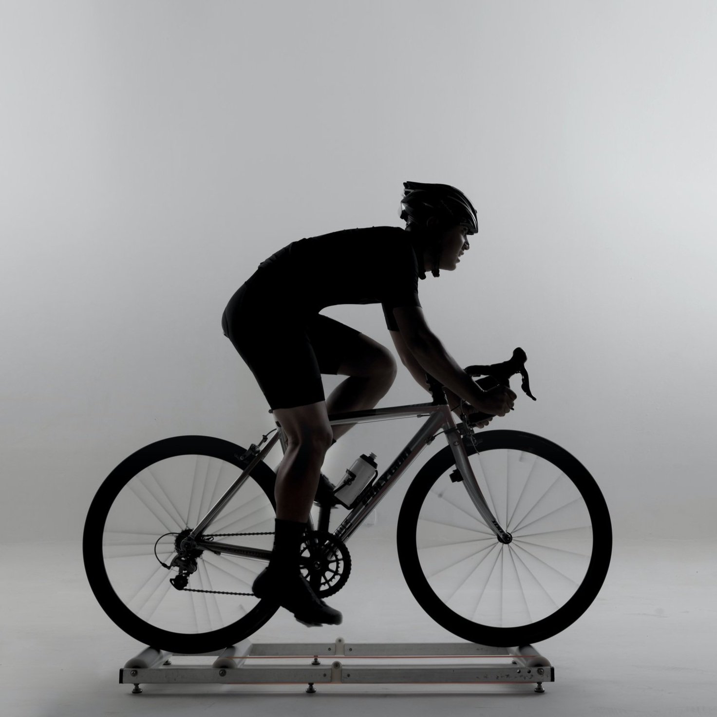 A black and white image of someone riding a bicycle indoors