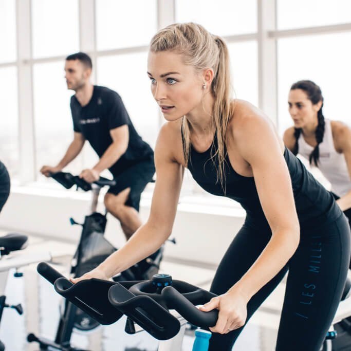 A group of people stationary cycling indoors 