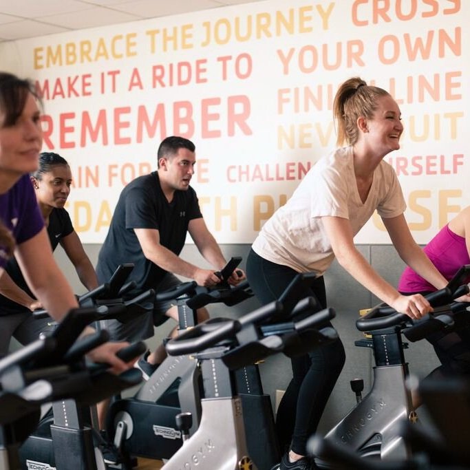 A group of people stationary cycling indoors 