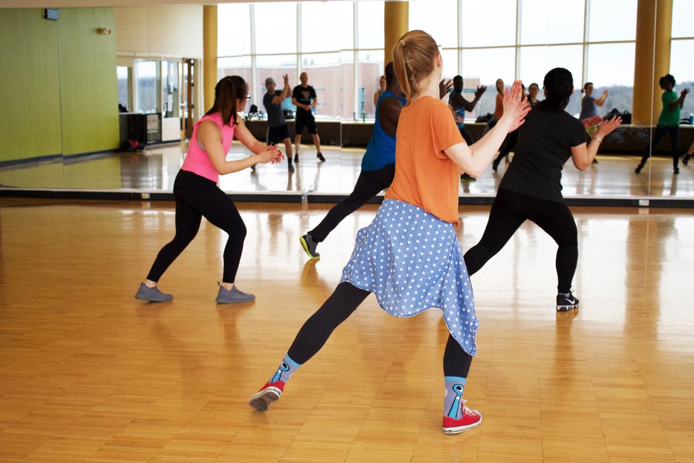 People dancing in front of a mirror in an indoor dance class