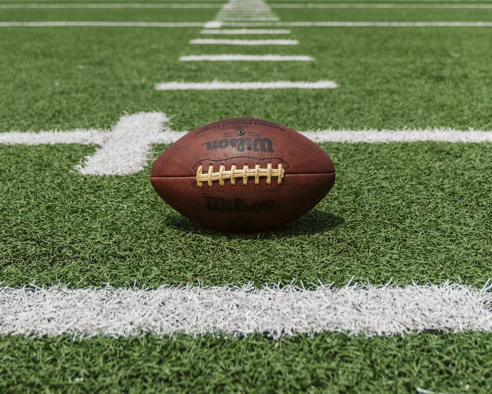 A football laying in the grass of a football field