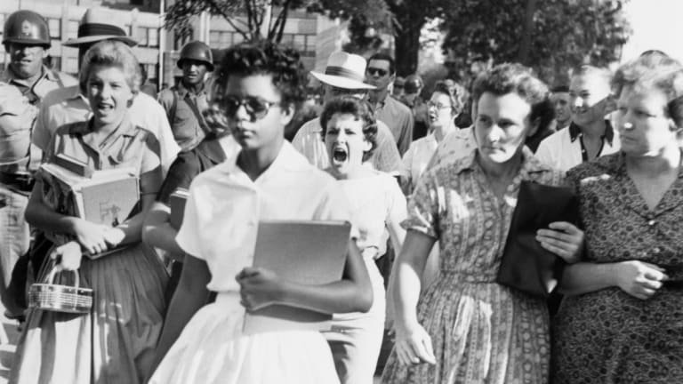 Black and white photograph of a group of a person walking away from a group of people