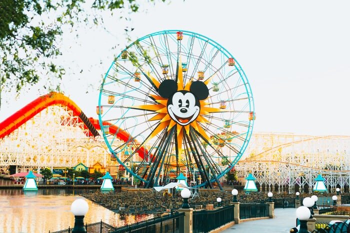 Disney outdoor theme park featuring a ferris wheel with Mickey Mouse's face on it 