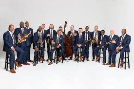 The members of the Lincoln Center Orchestra posing in formal attire with their instruments