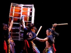 Members of Yamato The Drummers of Japan drumming on a large drum 