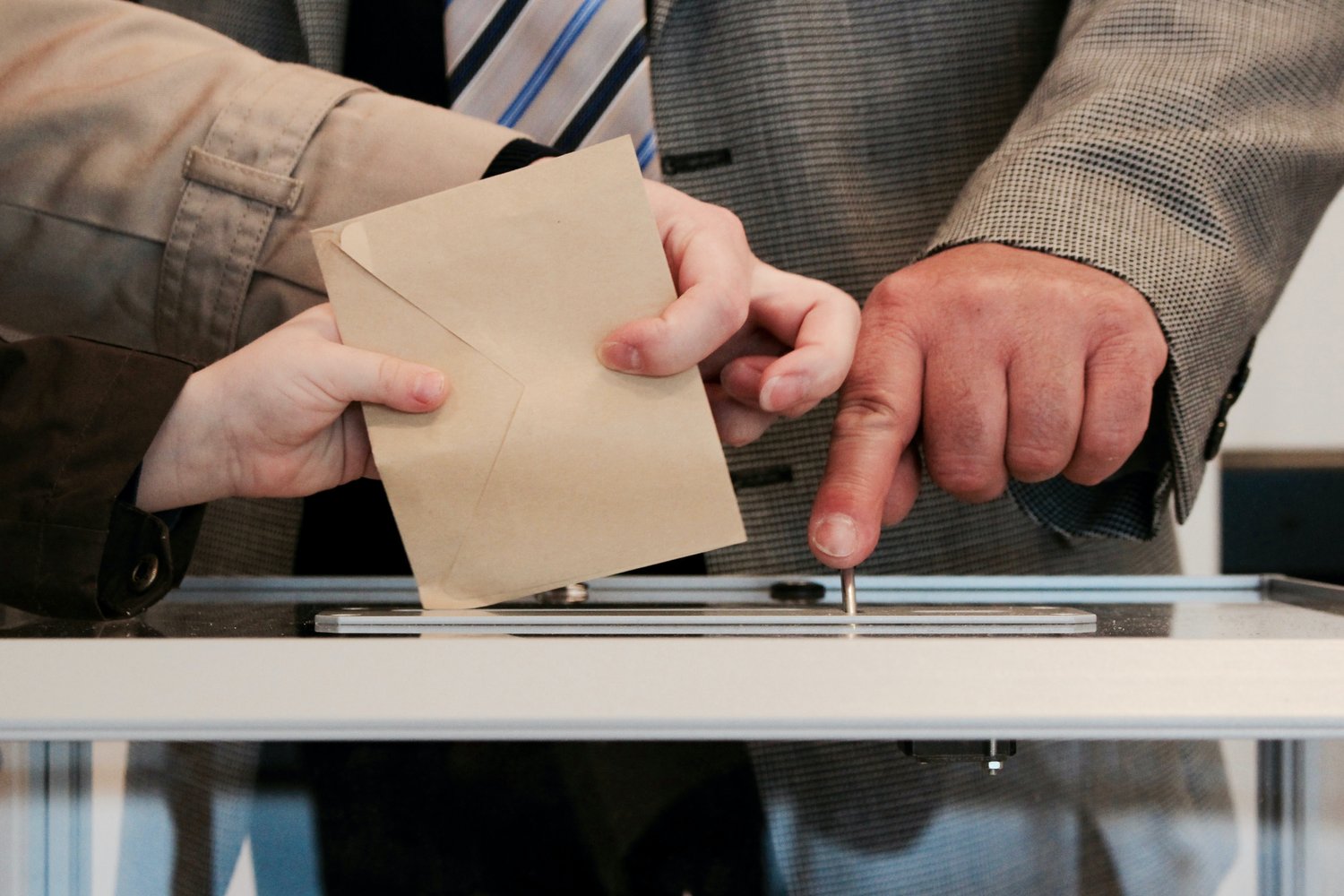Someone submitting an envelope into a ballot box