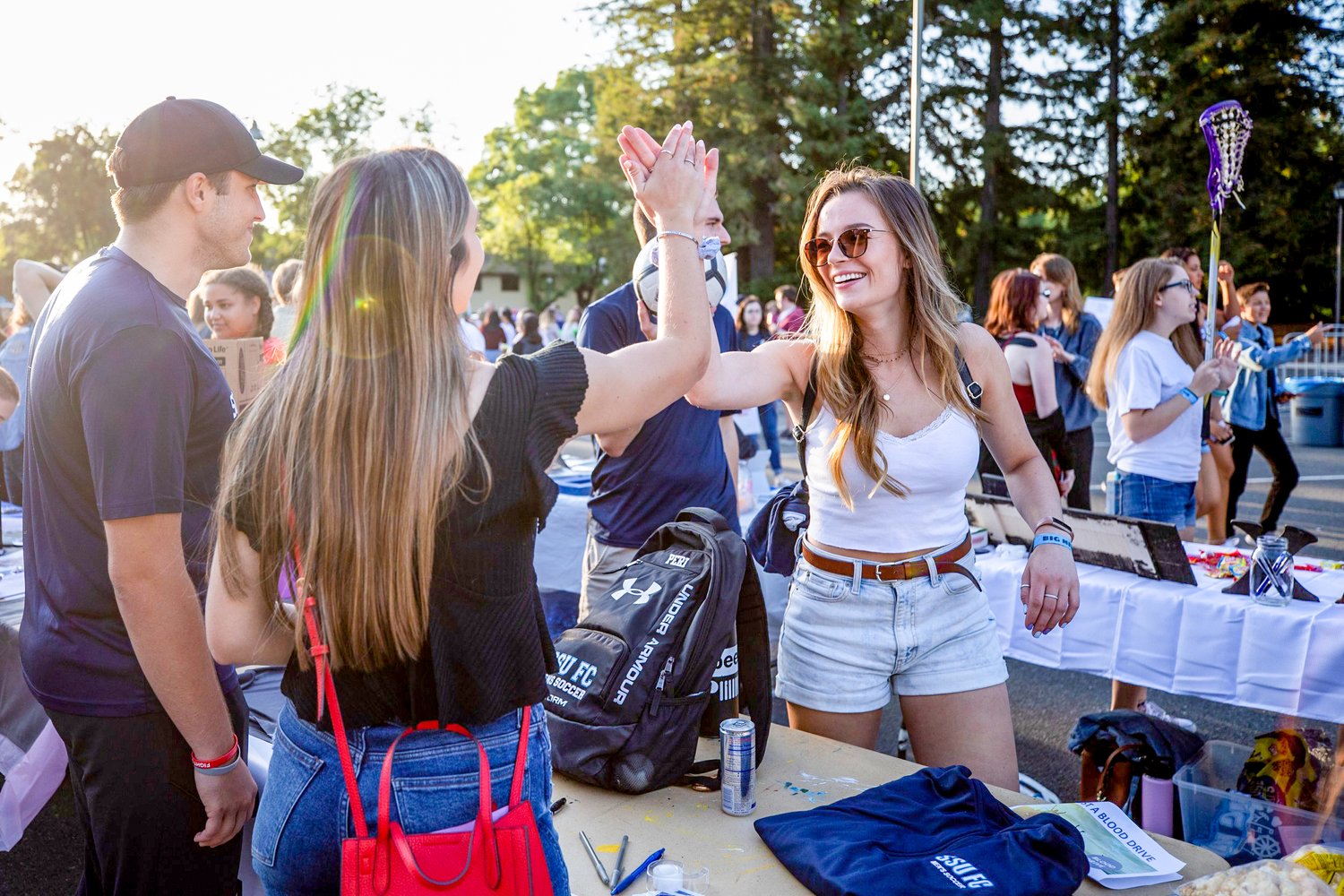 People smiling and high-fiving at a Greek Life event 