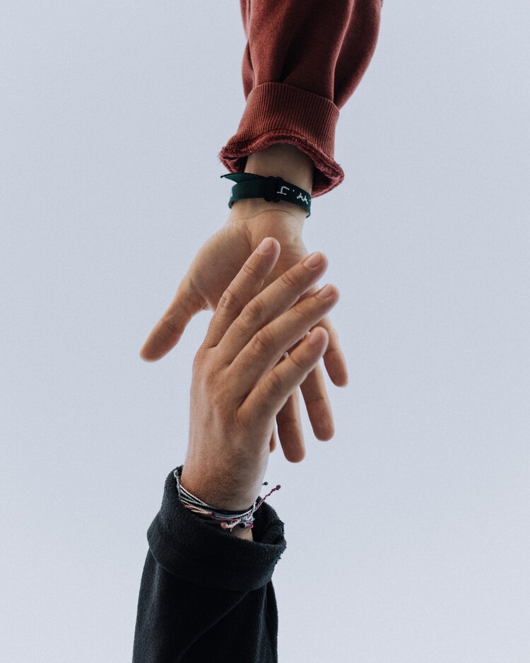 Two hands reaching out to embrace one another with the sky in the background