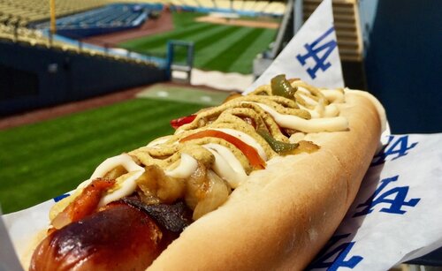 A condiment-covered hot dog with a baseball field in the background 