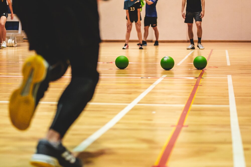 The legs of people playing a game of dodgeball indoors