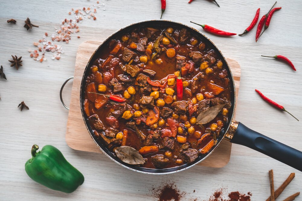 A pot of chili with peppers surrounding it