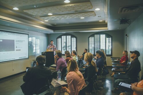 A group of people inside a classroom watching someone make a presentation