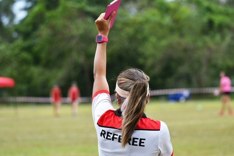 Someone wearing a referee shirt and holding up a book