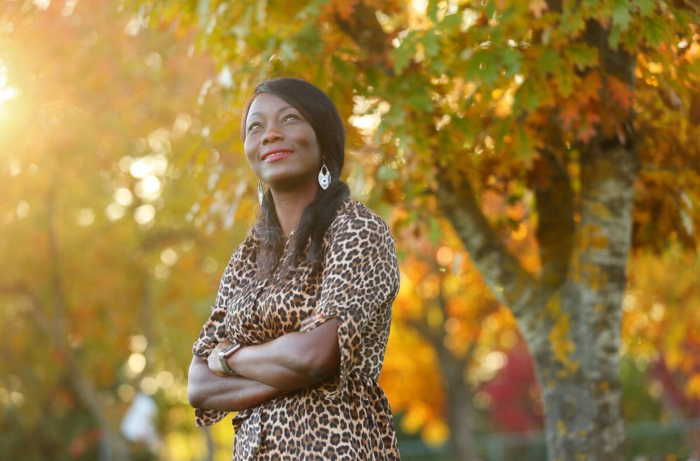 Jackie Elward crossing her arms and smiling in front of a background of yellow trees