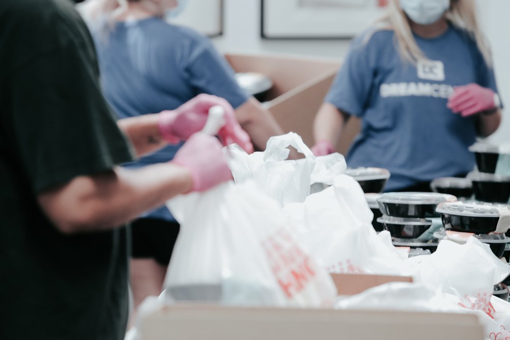 People performing community service while putting bags of food in boxes